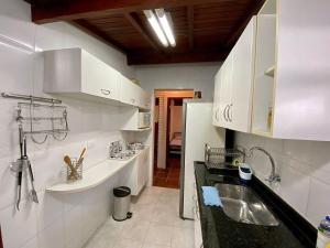 uma cozinha com armários brancos e um lavatório em Villa do Aconchego em Ubatuba