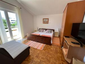 1 dormitorio con 1 cama y TV de pantalla plana en Apartmani Bosiljka en Nin