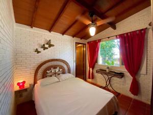 um quarto com uma cama com cortinas vermelhas e uma janela em Villa do Aconchego em Ubatuba