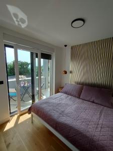 - une chambre avec un lit violet et un balcon dans l'établissement Seaside residence - Sunset Appartement, à Kožino