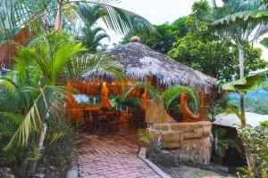 a restaurant with a thatched roof in a garden at Villeta Boutique Hotel Spa in Villeta