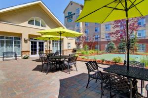 Homewood Suites by Hilton Toronto-Mississauga في ميسيساوغا: فناء به طاولات وكراسي به مظلات صفراء
