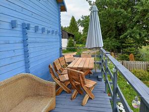 a wooden table and chairs on a deck with an umbrella at Świerkowe Siedlisko in Węgorzewo