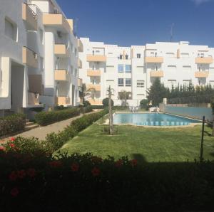 a large apartment building with a swimming pool in front of it at Appartement avec piscines, vue sur mer et accès à la plage à Achakar Hill, Tanger. in Tangier