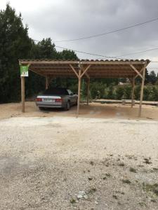 une voiture garée sous un pavillon en bois dans l'établissement Partie de mas en campagne, à Cavaillon