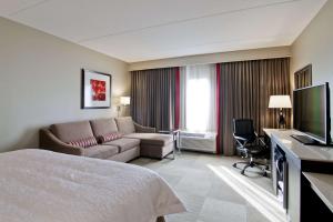 a hotel room with a bed and a couch and a television at Hampton Inn & Suites by Hilton Toronto Markham in Markham