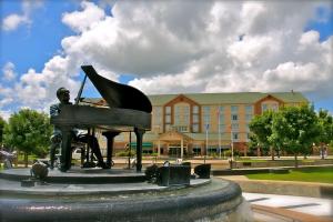 une statue d'un homme jouant du piano devant un bâtiment dans l'établissement Hilton Garden Inn Albany, à Albany