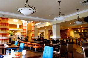 un restaurant avec des tables en bois, des chaises et des lumières dans l'établissement Hilton Garden Inn Albany, à Albany