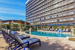 uma piscina de hotel com cadeiras e um edifício em Hilton Waco em Waco