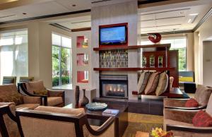 a living room with a fireplace and a tv at Hilton Garden Inn Albany Airport in Latham