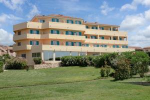 un grand bâtiment avec une pelouse devant lui dans l'établissement Hotel Castello, à Golfo Aranci