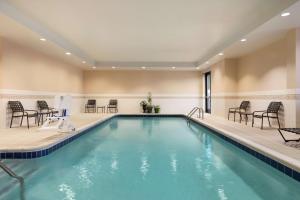 a pool in a hotel with chairs and tables at Hilton Garden Inn Troy in Troy