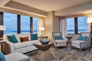 a living room with a couch and two chairs and windows at Hilton Anchorage in Anchorage