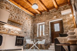 a kitchen with stone walls and a table and chairs at Petra Elounda Suites - Adults Only in Elounda