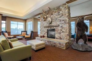a living room with a stone fireplace with a bear statue at Hilton Garden Inn Anchorage in Anchorage