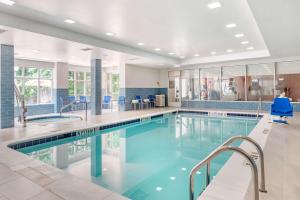 a swimming pool with blue chairs in a building at Hilton Garden Inn Atlanta Northeast/Gwinnett Sugarloaf in Duluth