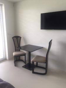 mesa y 2 sillas con TV en la pared en Ubytování SR, en Milovice