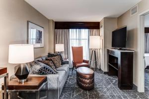 a living room with a couch and a tv at Embassy Suites Atlanta - Kennesaw Town Center in Kennesaw