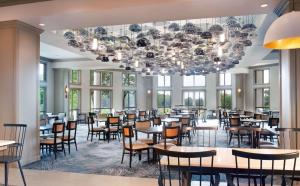 a dining room with tables and chairs and a chandelier at Hilton Atlanta/Marietta Hotel & Conference Center in Marietta