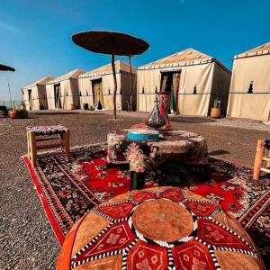 eine Gruppe von Zelten mit einem Tisch und einem Sonnenschirm in der Unterkunft Montazah yfrane taounate in Taounate