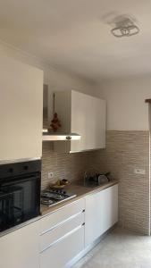 a kitchen with white cabinets and a stove at Happy house in Civitavecchia