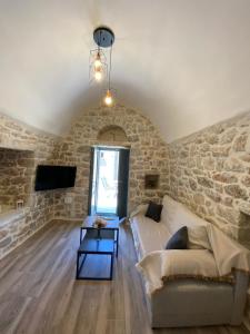 Mainotti's house with balcony في أريوبوليس: غرفة معيشة مع أريكة وجدار حجري