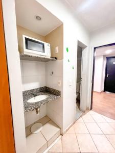 a bathroom with a sink and a microwave at Apart Hotel em Brasília - Garvey Park Hotel in Brasilia