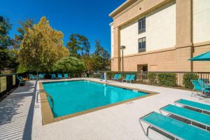 une piscine avec des chaises et un bâtiment dans l'établissement Hampton Inn & Suites Opelika-I-85 Auburn Area, à Opelika