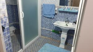 a blue tiled bathroom with a sink and a shower at Villa 250 m2 terrasse plus Garage in Mostaganem