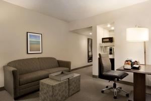 a living room with a couch and a desk and a chair at Embassy Suites Boca Raton in Boca Raton