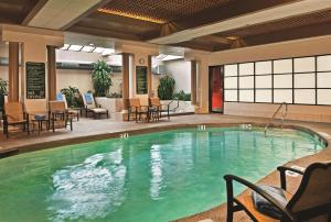 una piscina en el vestíbulo del hotel con sillas y mesas en Embassy Suites Baltimore - North/Hunt Valley, en Hunt Valley