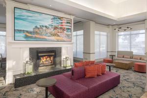 a living room with a purple couch and a fireplace at Hilton Garden Inn Boca Raton in Boca Raton