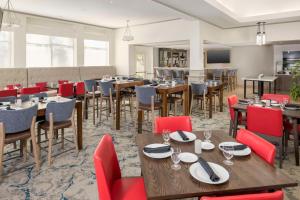un restaurante con mesas de madera y sillas rojas en Hilton Garden Inn Boca Raton, en Boca Raton