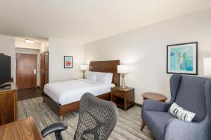 a hotel room with a bed and two chairs at Hilton Garden Inn Boca Raton in Boca Raton