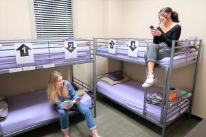 two girls sitting on bunk beds in a room at City House New Orleans Samesun in New Orleans