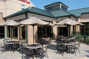 an outdoor patio with tables and chairs with umbrellas at Hilton Garden Inn Bowling Green in Bowling Green