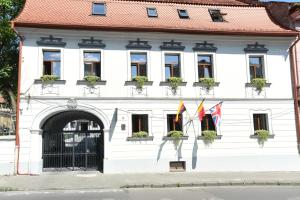 een wit gebouw met vlaggen ervoor bij Prinz Gregor in Braşov