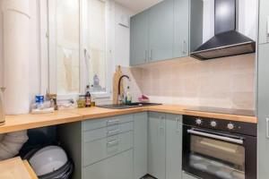 una cucina con armadi bianchi e ripiano in legno di New Entiry apartment-Private rooms in Paris a Parigi