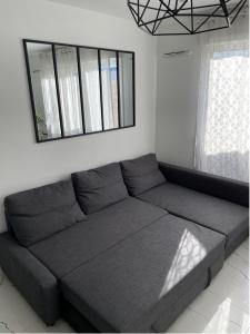 un divano in soggiorno con specchio di Grand F3 à 30mn de Paris - Terrasse + Parking privé a Saint-Ouen-lʼAumône