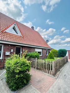 a red brick house with a wooden fence at Behagliches Haus mit Kamin in Rechtsupweg