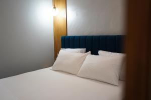 Bett mit weißen Kissen und blauem Kopfteil in der Unterkunft Hotel DelMar in Golem