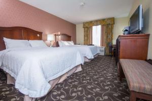 a hotel room with two beds and a flat screen tv at Hampton by Hilton Brattleboro in Brattleboro