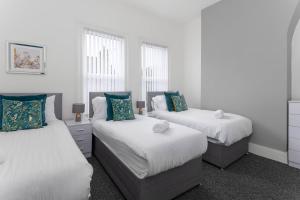 a bedroom with two beds and two windows at Woodbine House - Air Host and Stay - Free parking - Contractor Friendly in Liverpool