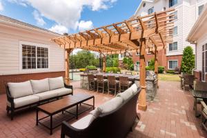 eine Terrasse mit einer hölzernen Pergola sowie Tischen und Stühlen in der Unterkunft Homewood Suites by Hilton Buffalo-Amherst in Amherst