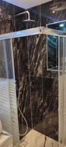 a bathroom with a shower with a black marble wall at Ilia’s Guesthouse in Pogradec
