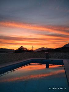 a swimming pool with a sunset in the background at Vila Rogač in Tivat