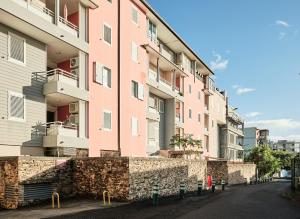 różowy budynek z kamienną ścianą obok ulicy w obiekcie Appart'Eden : vue panoramique sur Saint-Denis w mieście Sainte-Clotilde