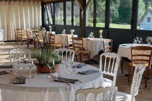 a room with tables and chairs with white tablecloths at B&B Le Clos du Phare - En campagne in Saint-Samson-de-la-Roque