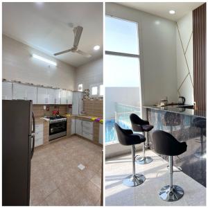 a kitchen with a black refrigerator and two black stools at Al Saad chalet in Al Ashkharah