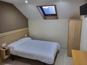 a small bedroom with a bed and a window at CASA MARUXA pensión in Pontevedra